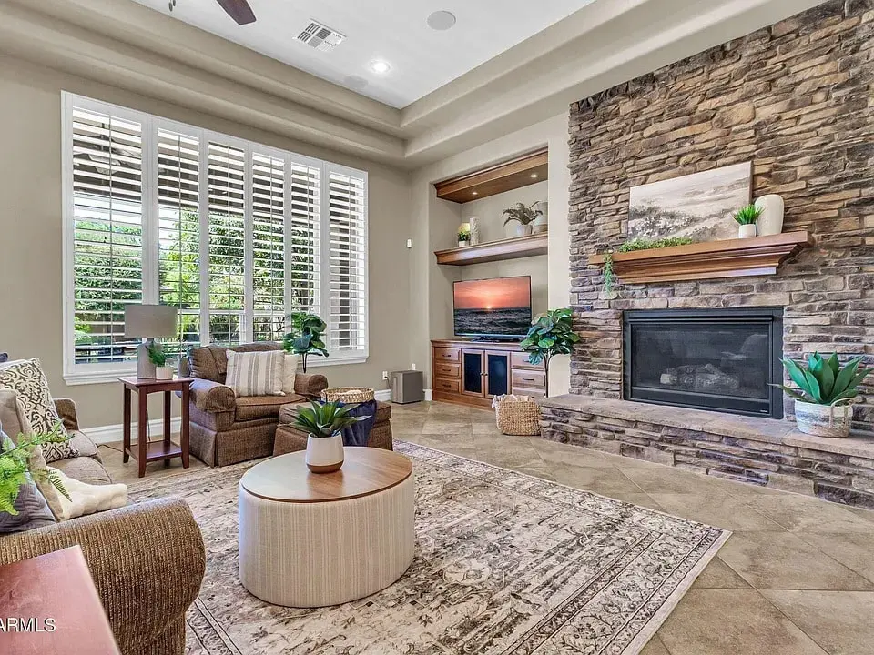 Spacious living room with stone fireplace, large windows, and modern decor.