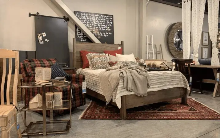 Cozy bedroom with a wooden bed, plaid armchair, and decorative pillows on a patterned rug.