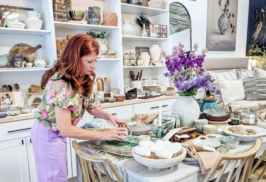 Woman arranging decorative items on a table in a home decor store.