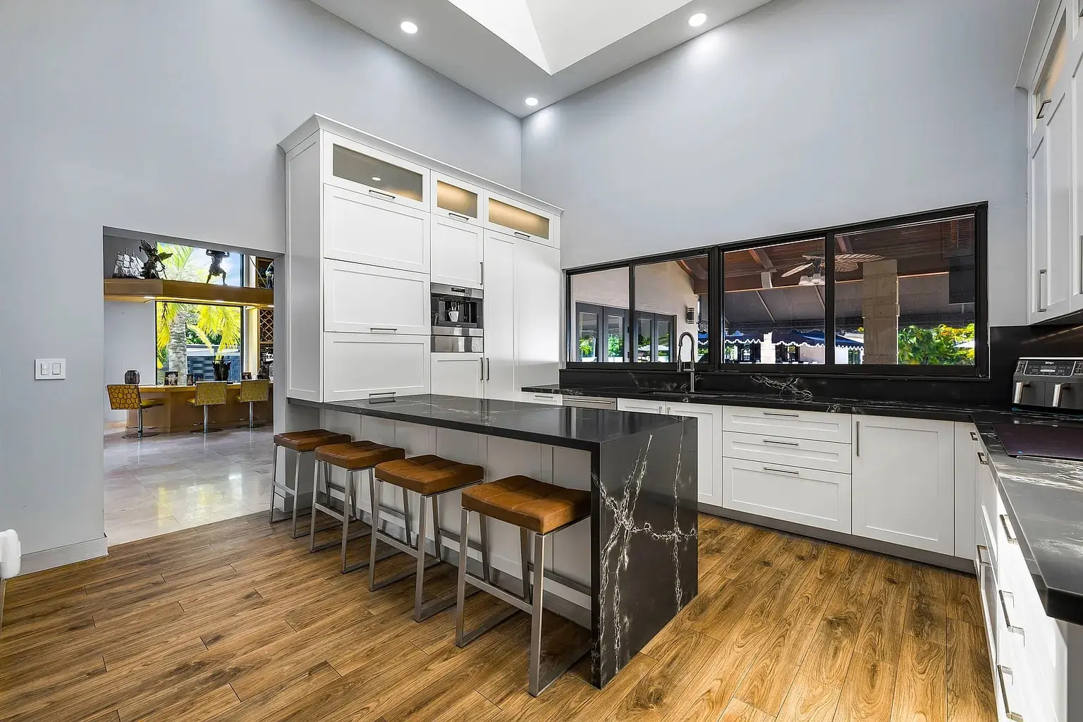 Modern kitchen with white cabinets, black countertops, and a central island with four stools.
