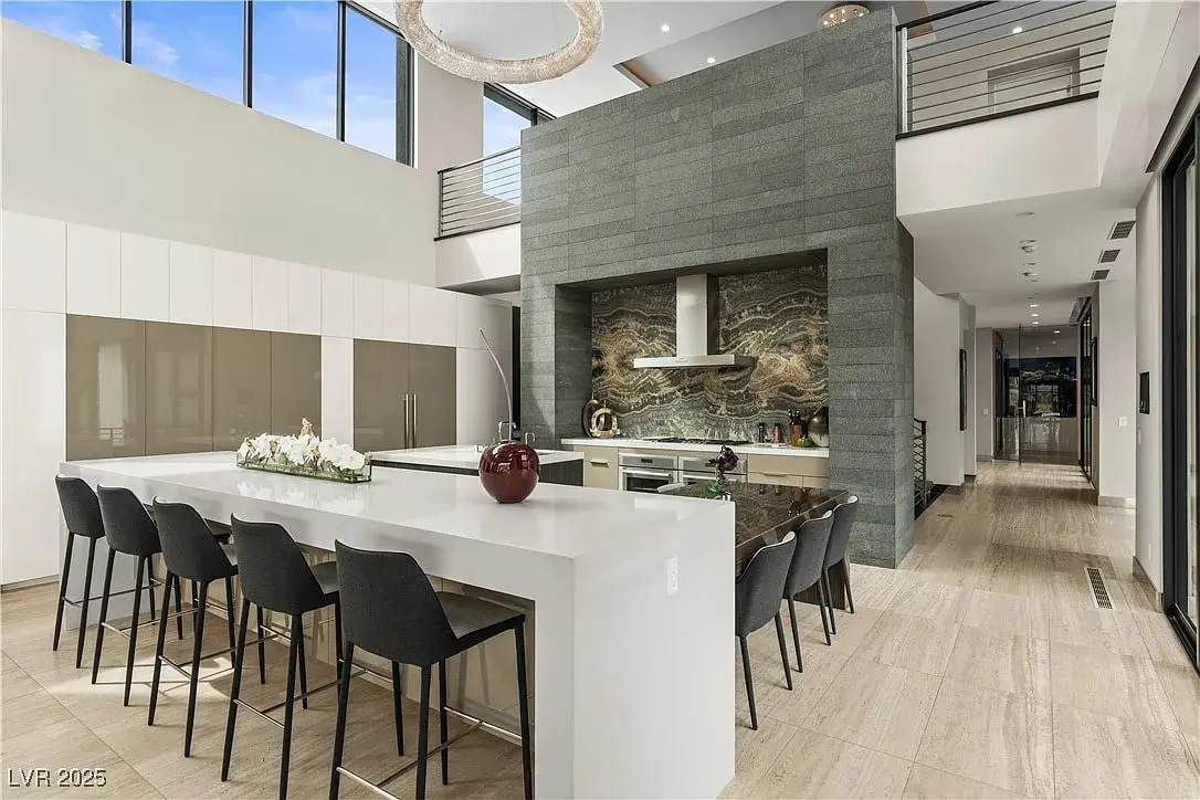 Modern kitchen with a large island, bar stools, and a marble backsplash.