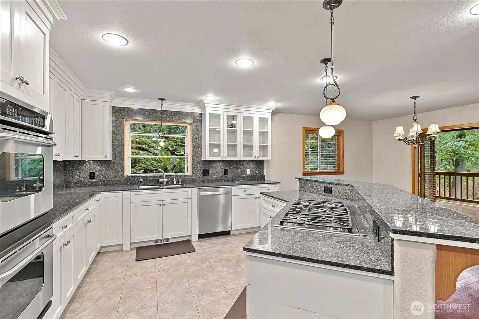 Modern kitchen with white cabinets, granite countertops, stainless steel appliances, and large windows.