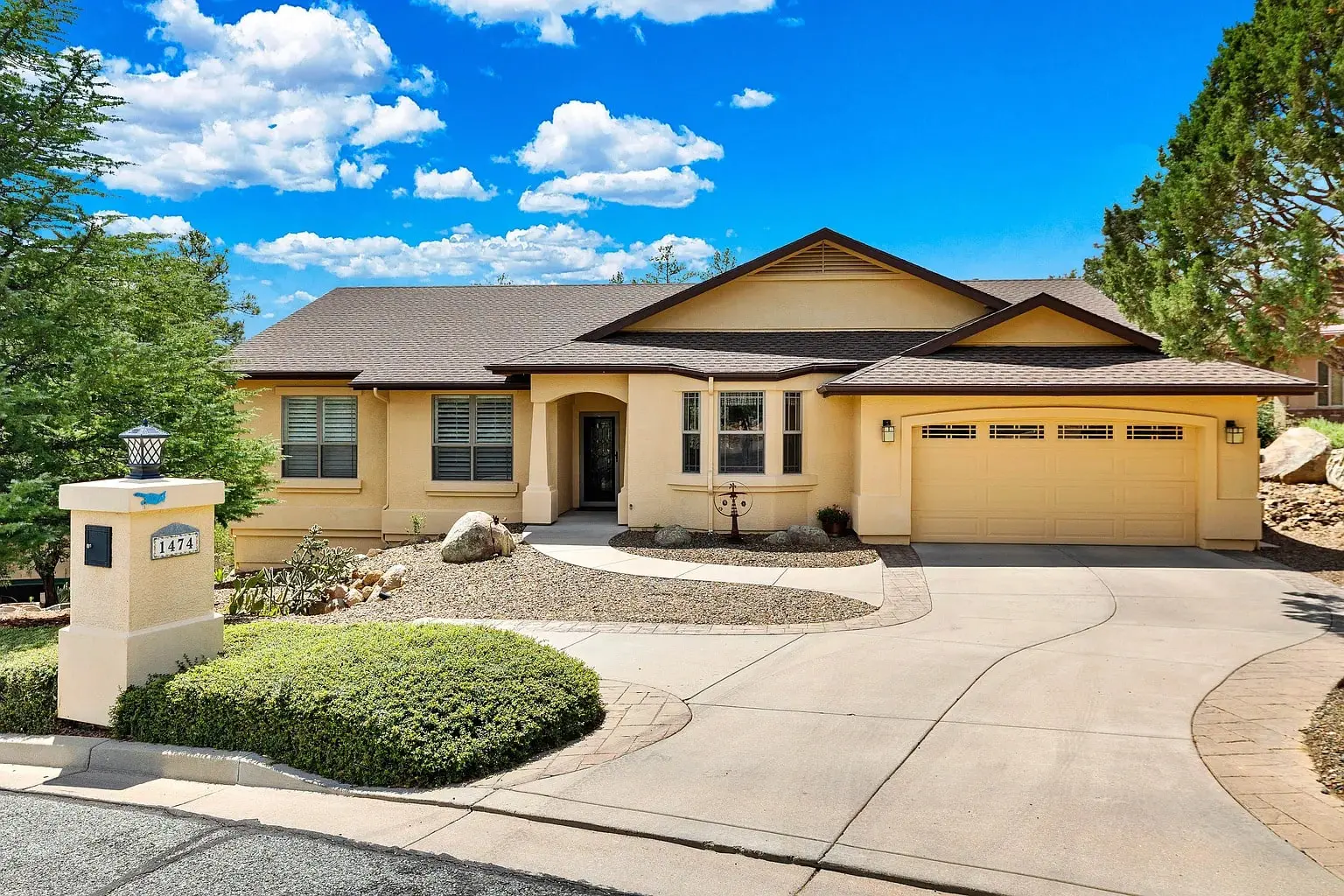 Single-story yellow house with a two-car garage and landscaped front yard.