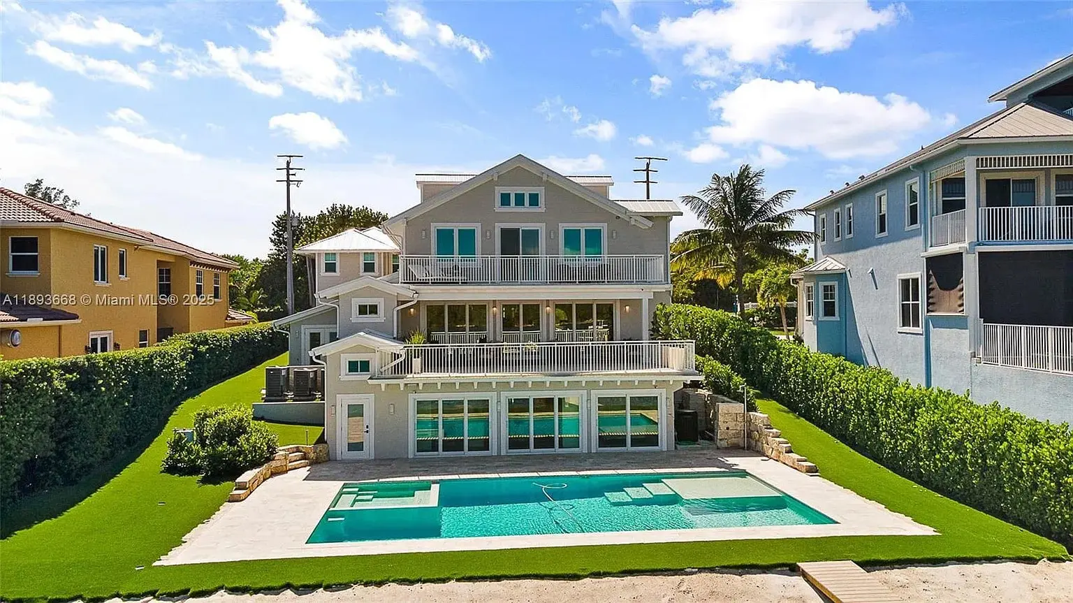 Three-story house with large windows, balconies, and a swimming pool in the backyard.