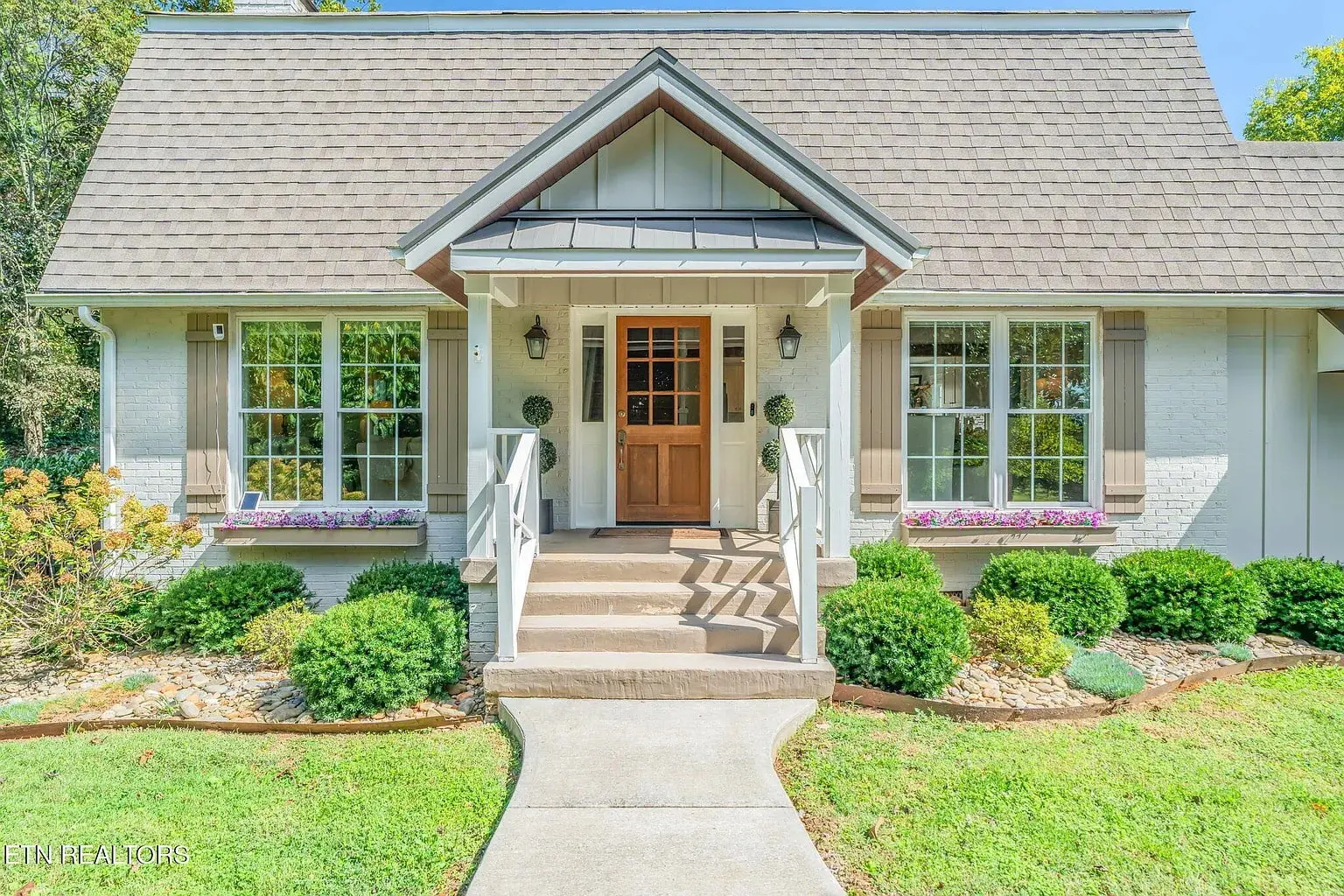 Charming white house with a gabled roof, front porch, and manicured garden.