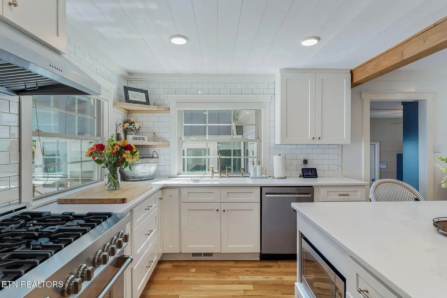 Bright kitchen with white cabinets, stainless steel appliances, and a vase of flowers on the counter.