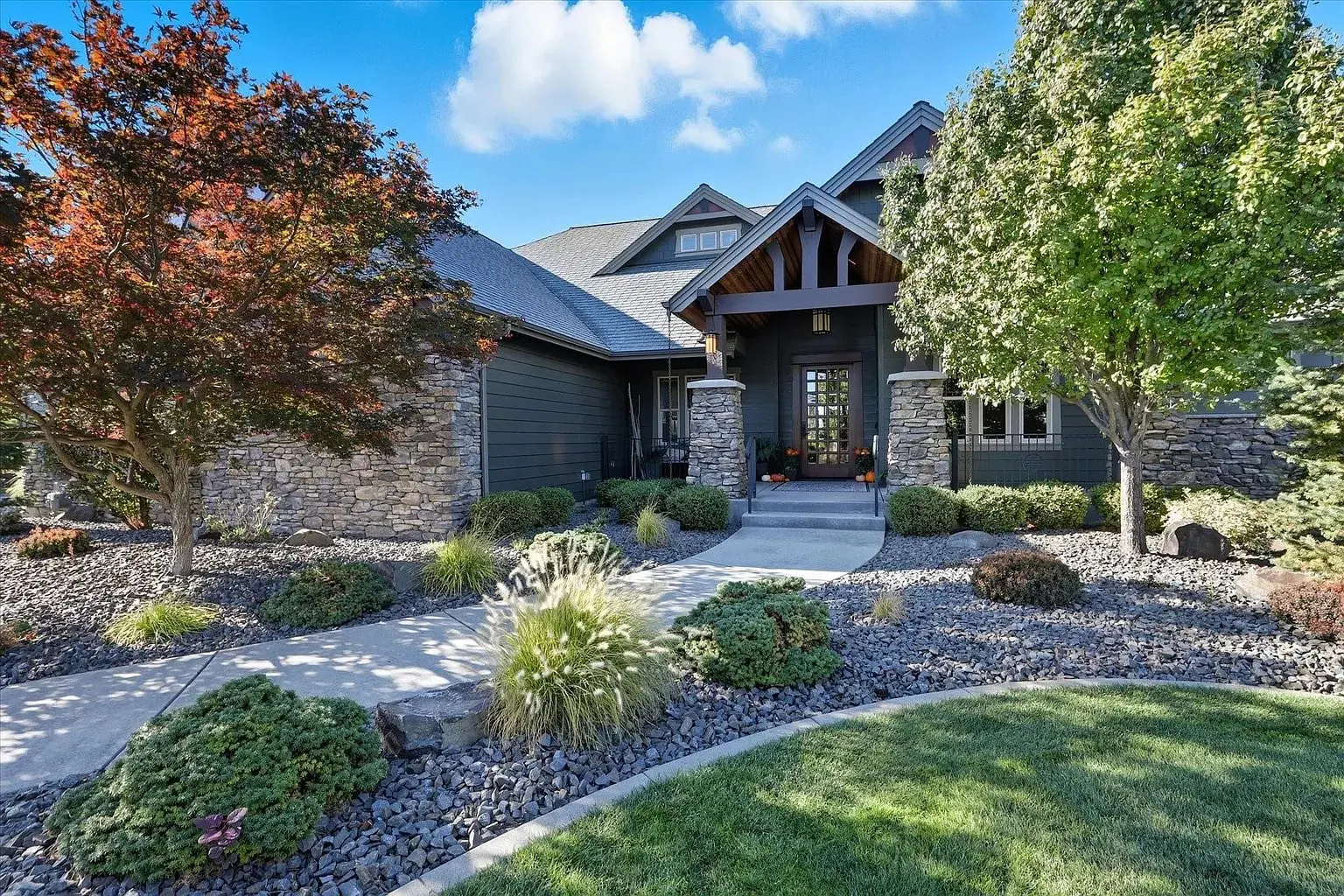 Modern house with stone facade, landscaped garden, and pathway leading to the front door.