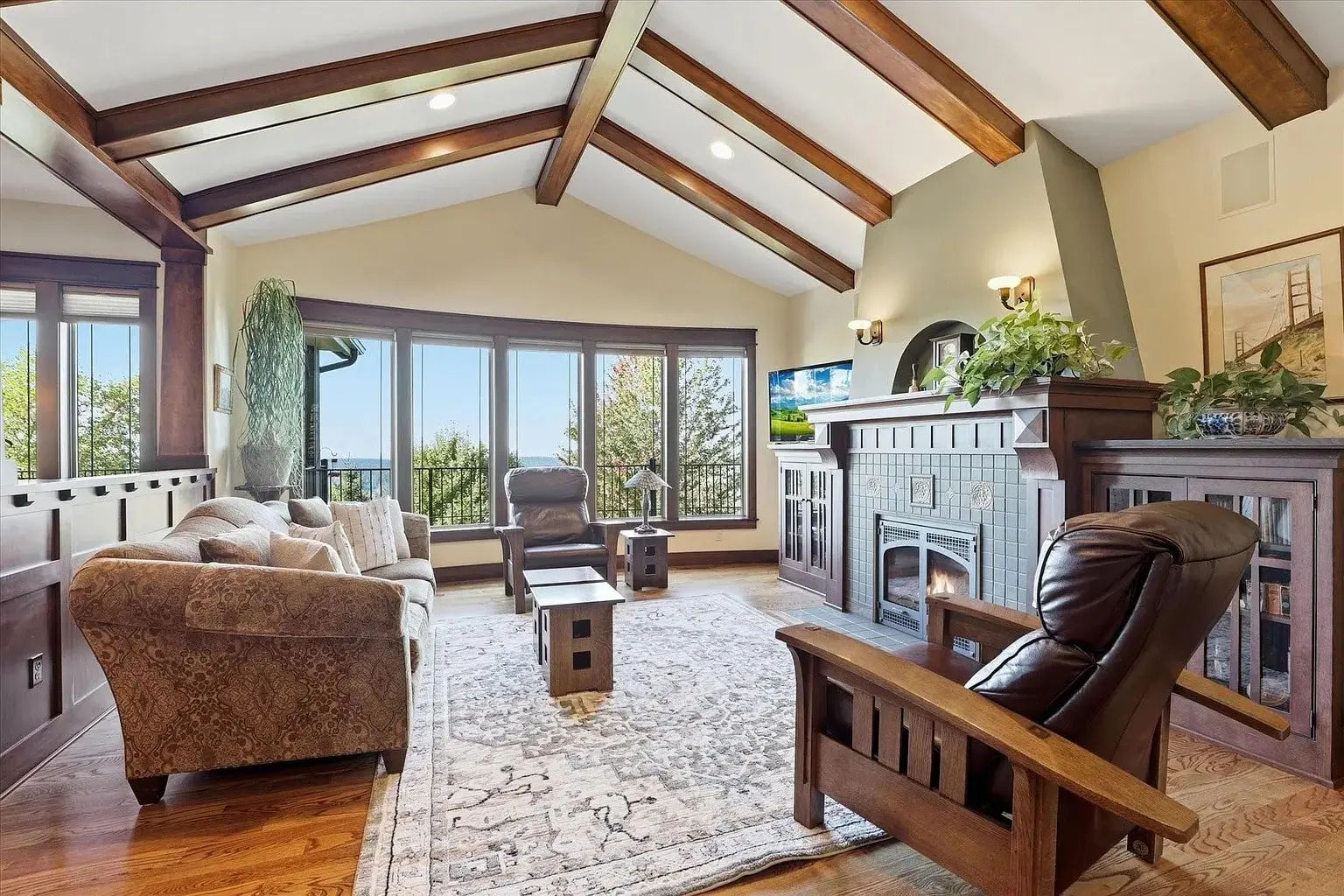 Cozy living room with vaulted ceiling, large windows, fireplace, and comfortable seating.