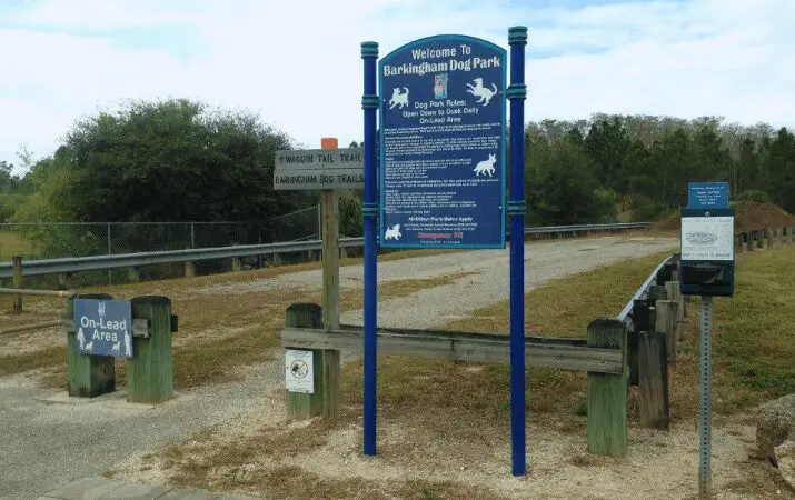 Sign for 'Barkingham Dog Park' with rules, surrounded by trees and pathways.