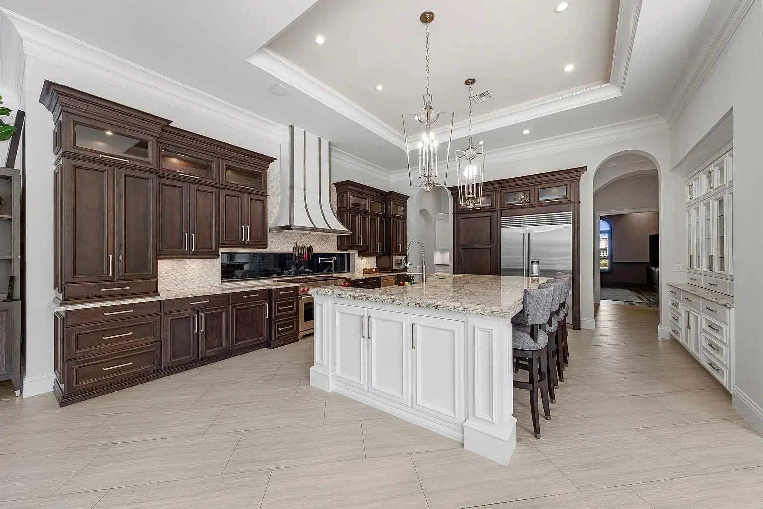 Spacious modern kitchen with dark wood cabinets, large island, and stainless steel appliances.