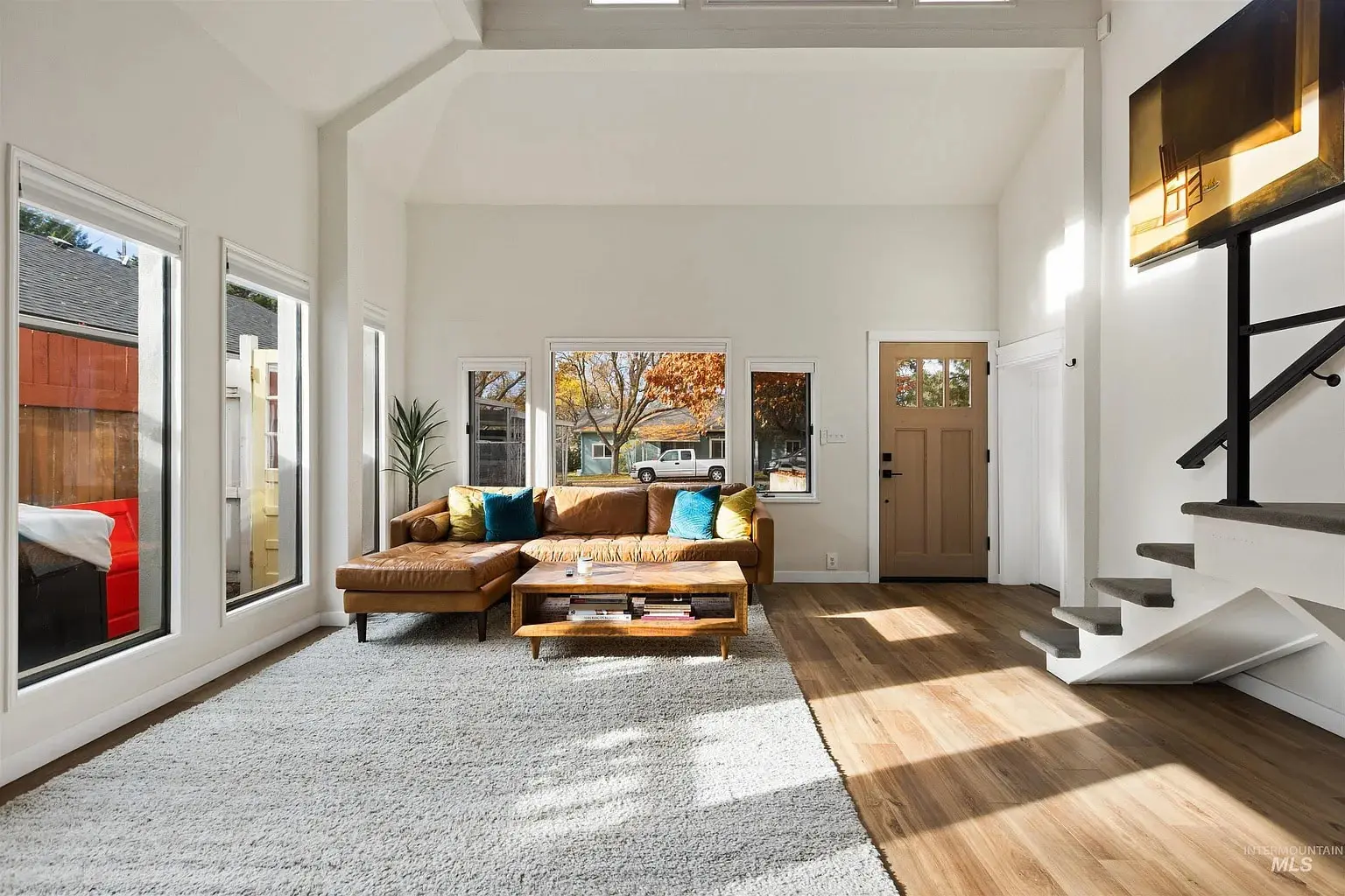Spacious living room with a brown sectional sofa, large windows, and a wall-mounted TV.