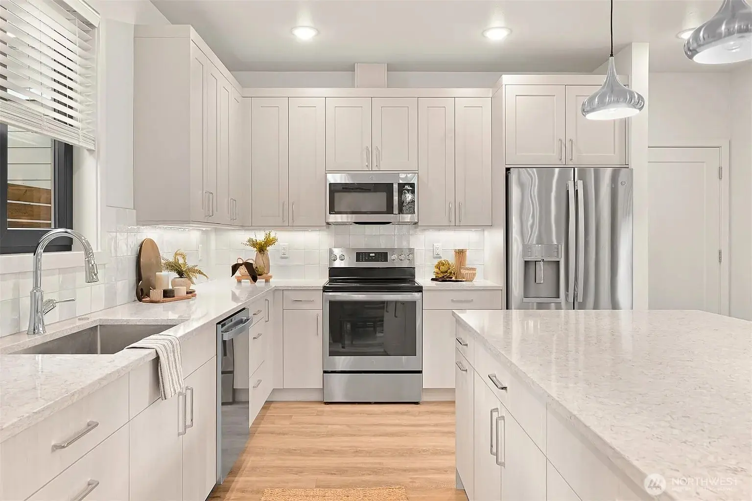 Modern kitchen with white cabinets, stainless steel appliances, and a central island with pendant lights.