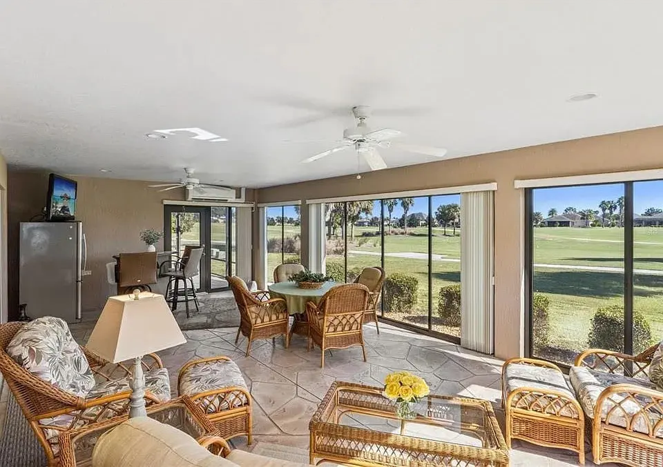 Sunroom with wicker furniture, large windows, and a view of a golf course.
