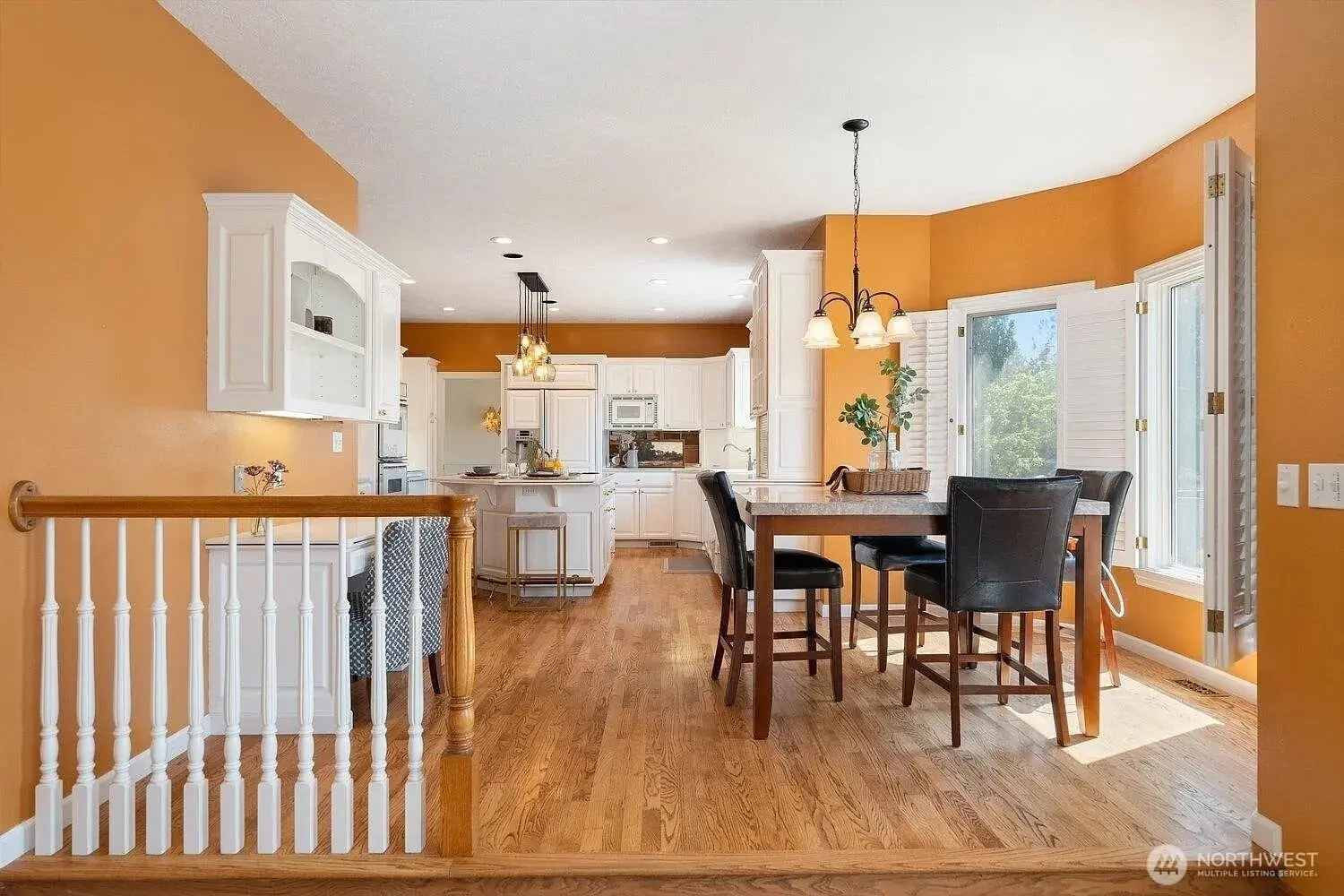 Spacious kitchen and dining area with orange walls, white cabinets, and wooden flooring.