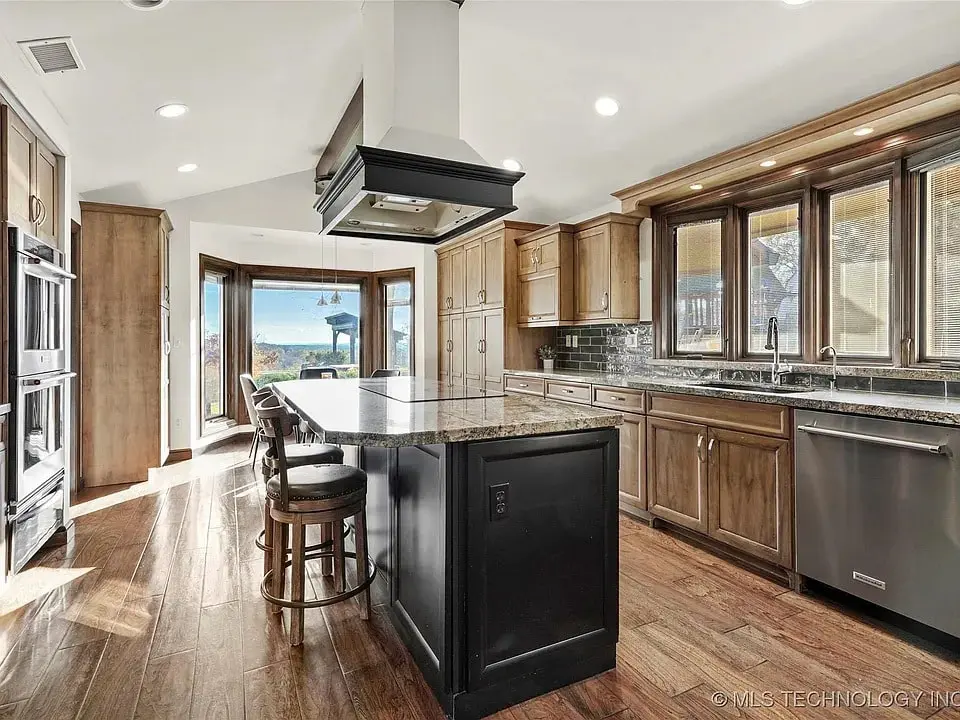 Spacious kitchen with wooden cabinets, central island, and large windows overlooking a scenic view.