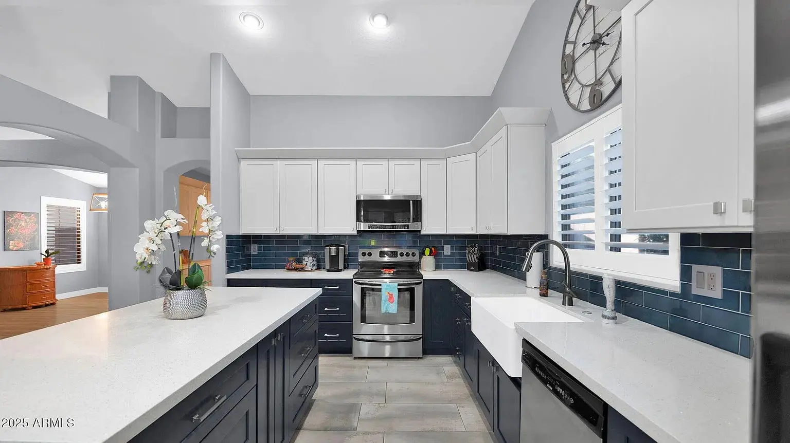 Modern kitchen with white and navy cabinets, stainless steel appliances, and blue tile backsplash.