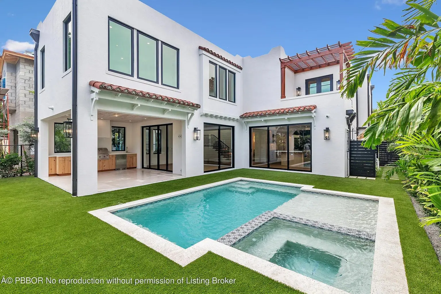 Modern white house with large windows, a small pool, and green artificial grass in the backyard.