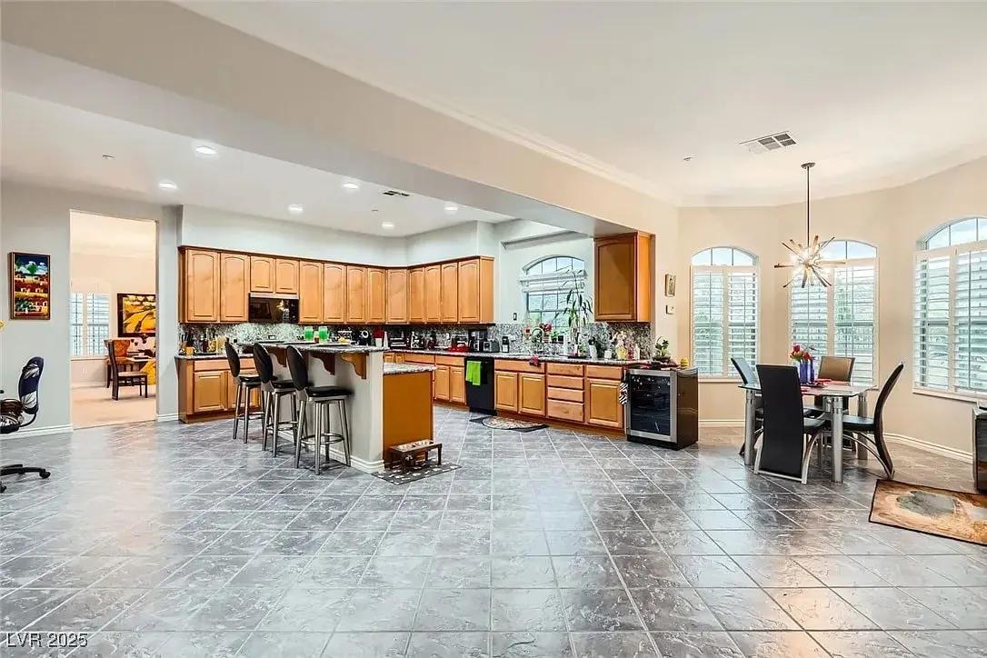 Spacious kitchen with wooden cabinets, large island, dining area, and tiled flooring.