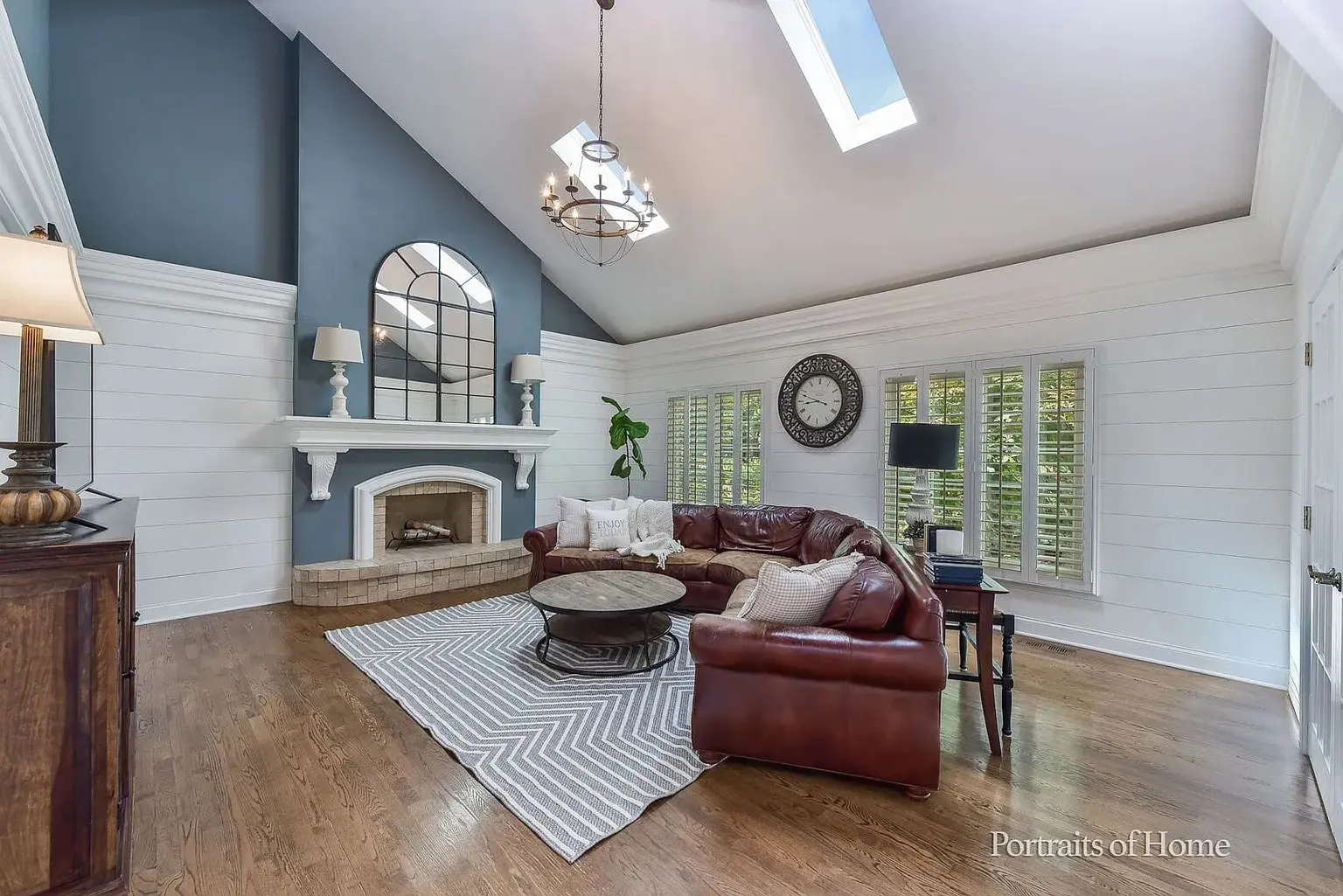 Spacious living room with vaulted ceiling, leather sectional, fireplace, and large window.
