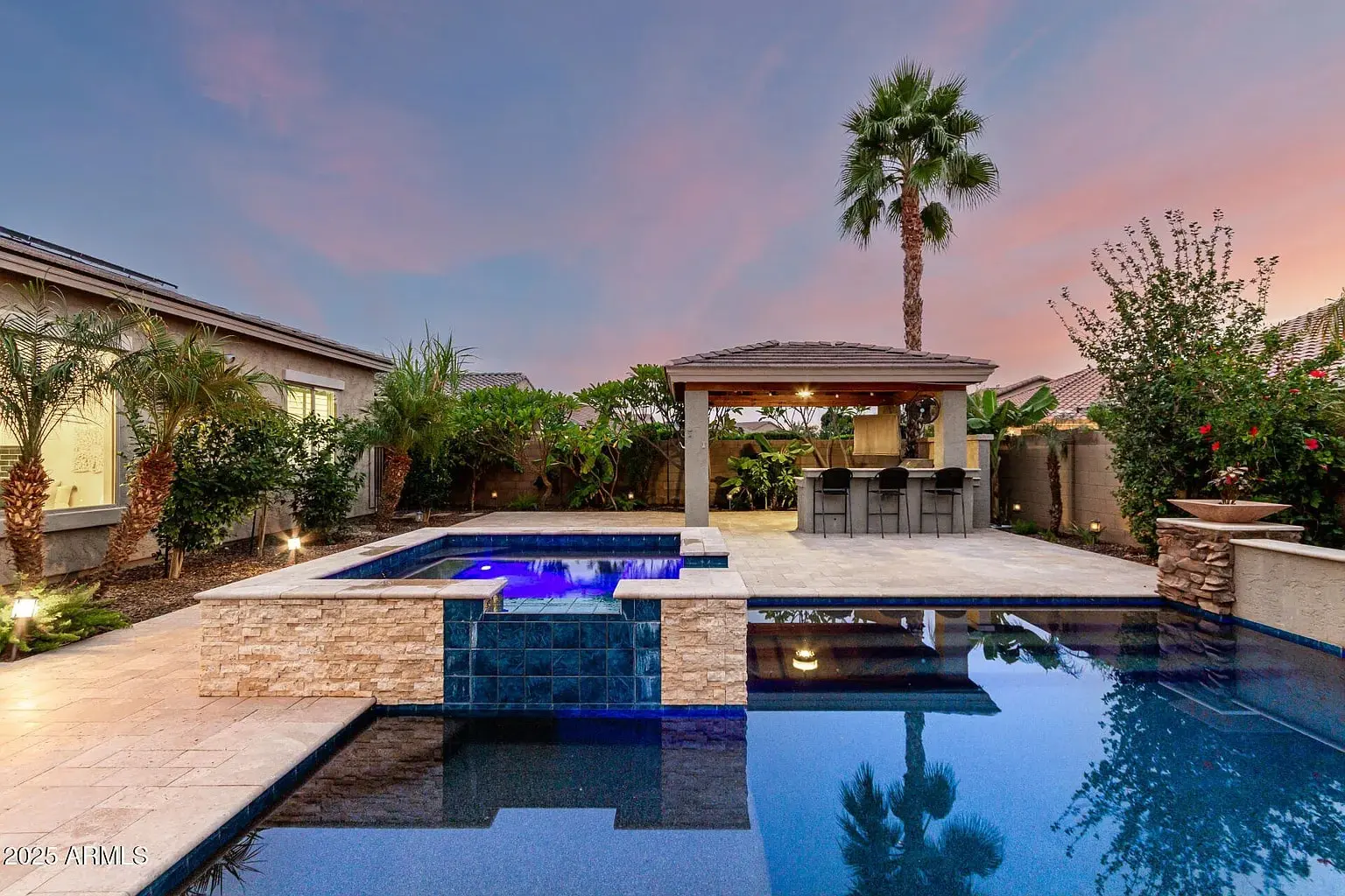 Backyard with a pool, hot tub, and covered patio bar area, surrounded by palm trees.