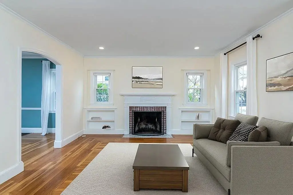 Living room with a fireplace, gray sofa, wooden coffee table, and artwork on the walls.