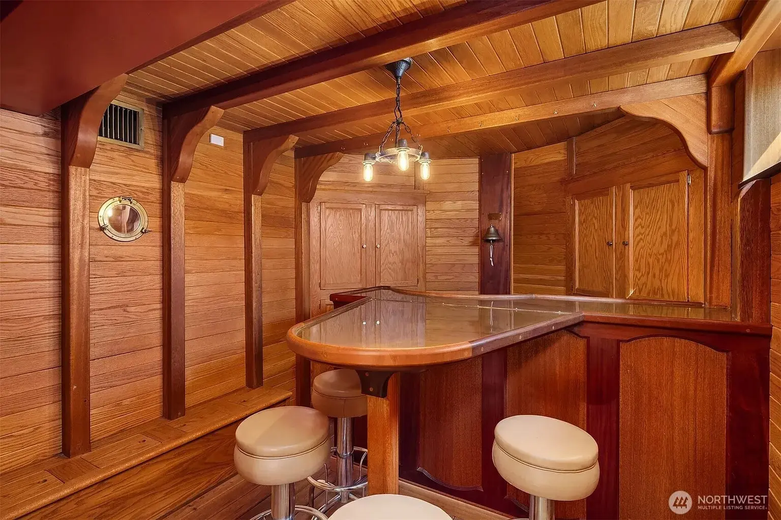 Wood-paneled room with a bar counter, stools, and nautical-themed decor.