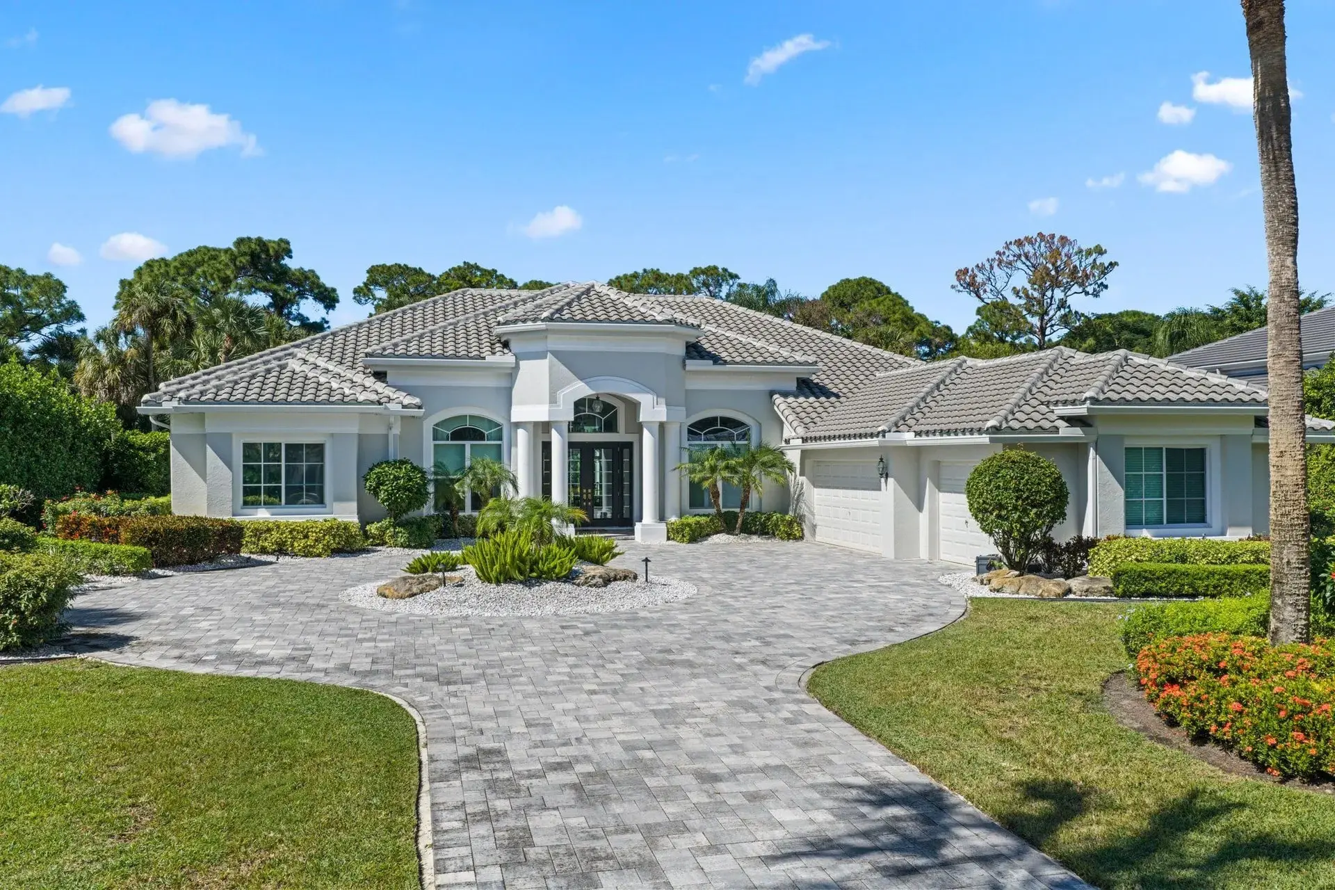 Single-story house with a tiled roof, circular driveway, and landscaped front yard.