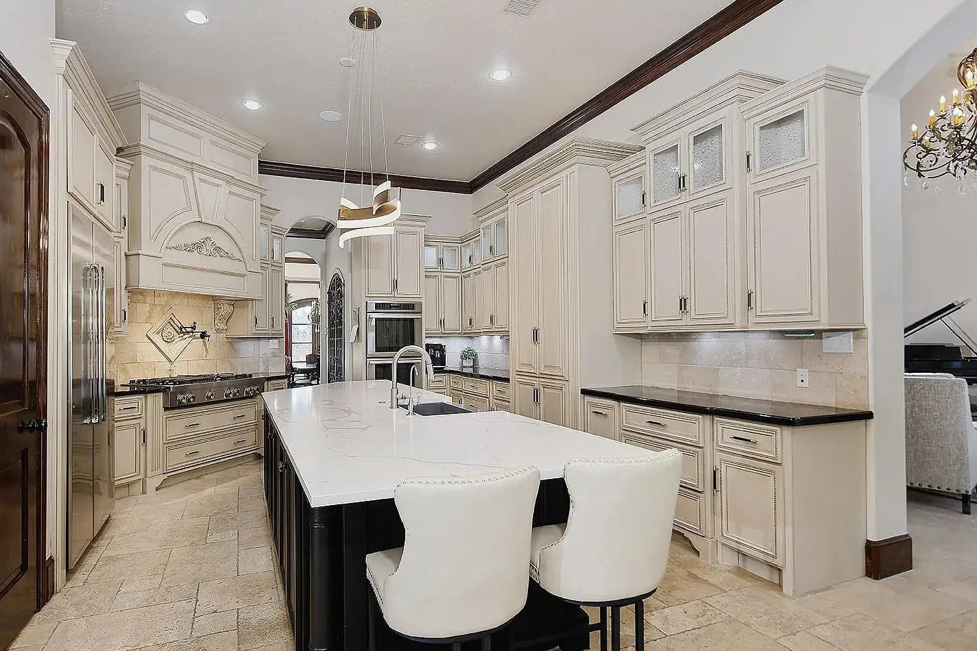 Spacious kitchen with white cabinets, large island, and modern pendant lighting.