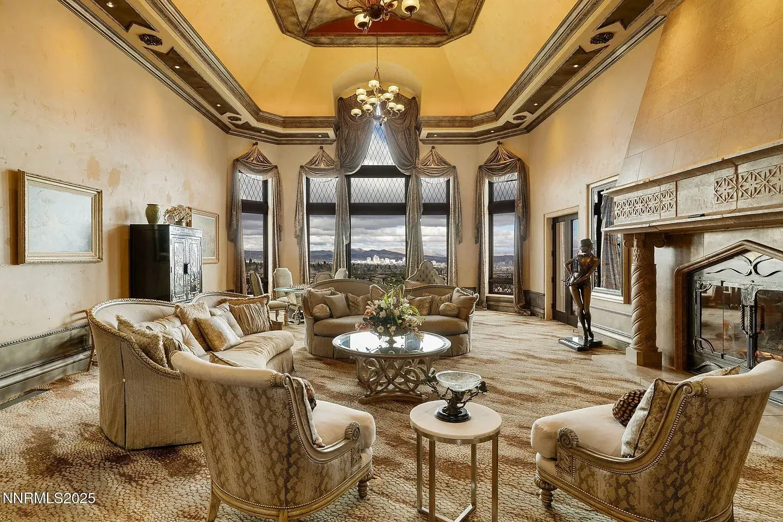 Luxurious living room with elegant furniture, large windows, and a grand fireplace.