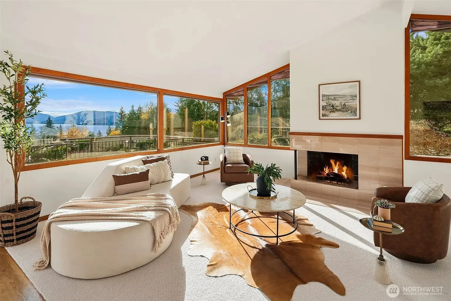 Modern living room with large windows, mountain view, fireplace, and cozy seating area.