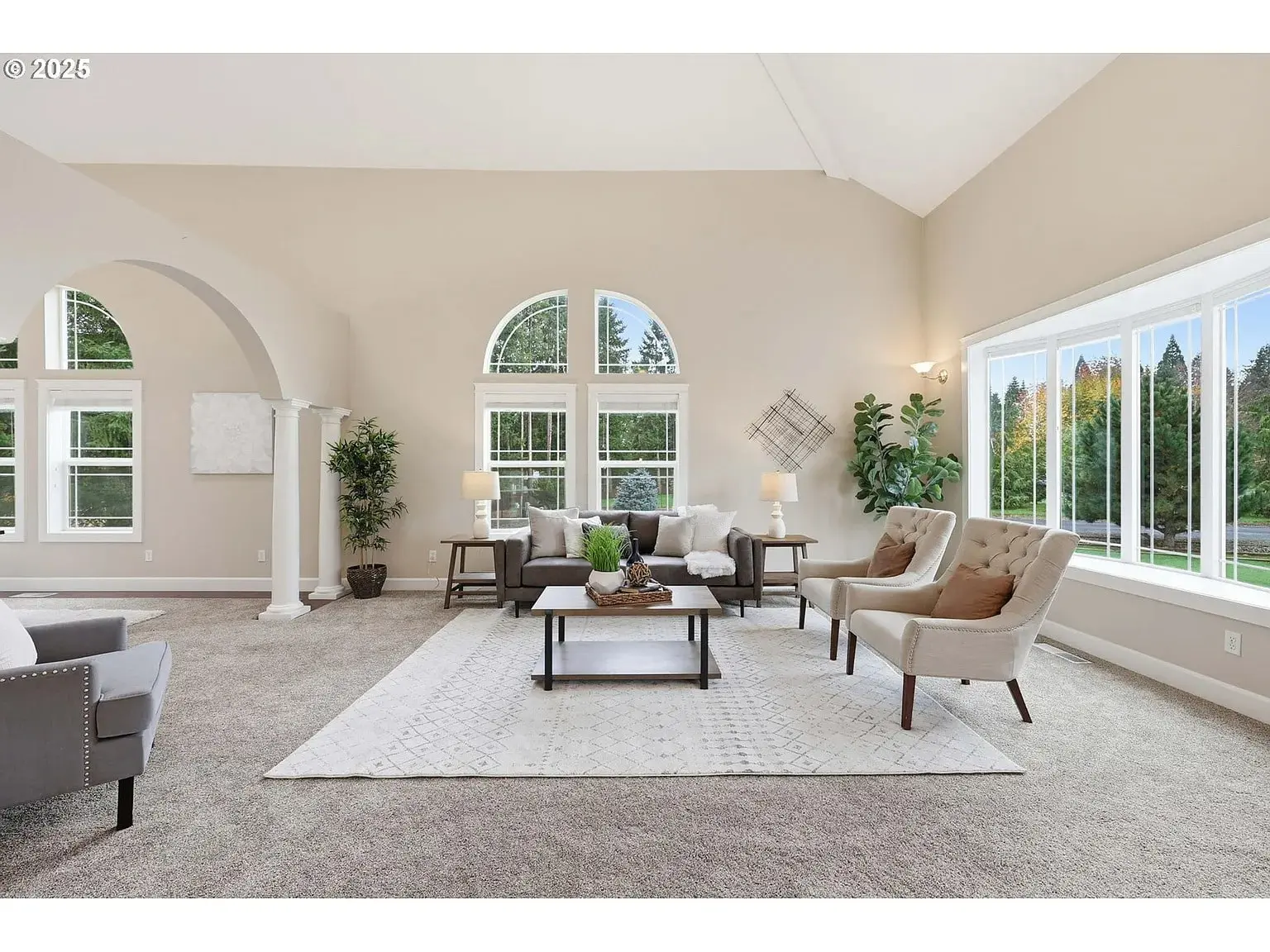 Spacious living room with large windows, neutral decor, and modern furniture.