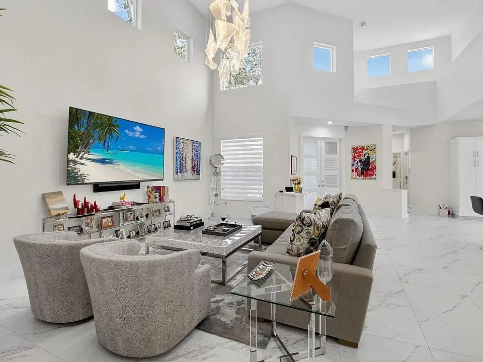Modern living room with gray sofas, a large TV, and a unique ceiling light fixture.