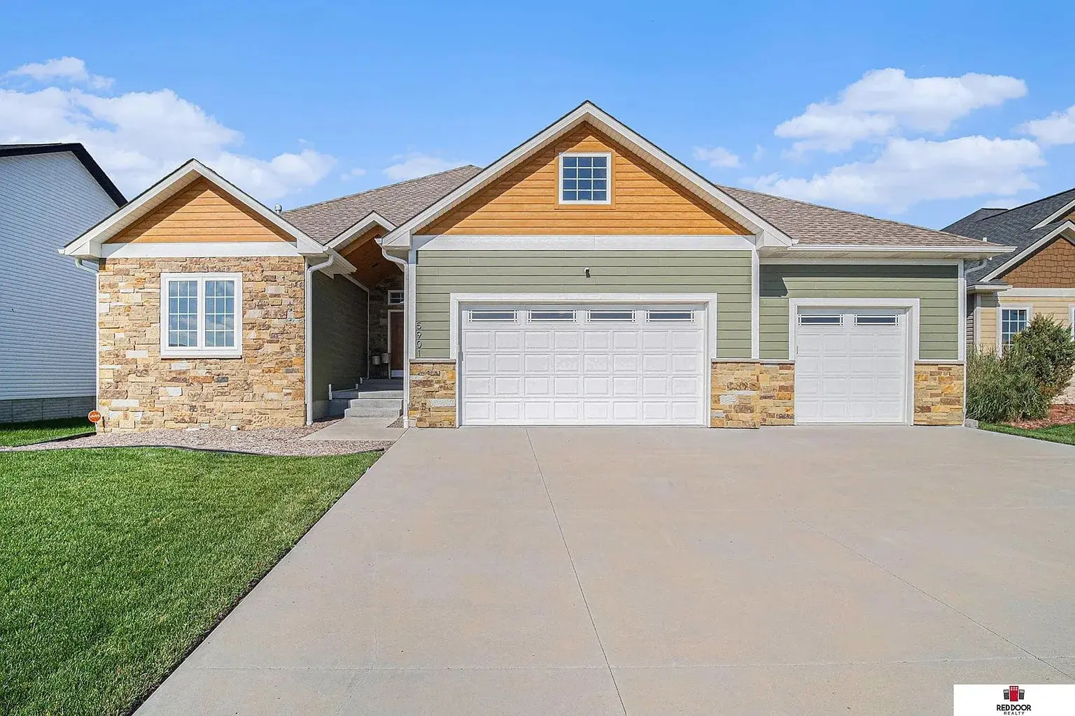 Single-story house with stone and wood accents, large driveway, and a two-car garage.