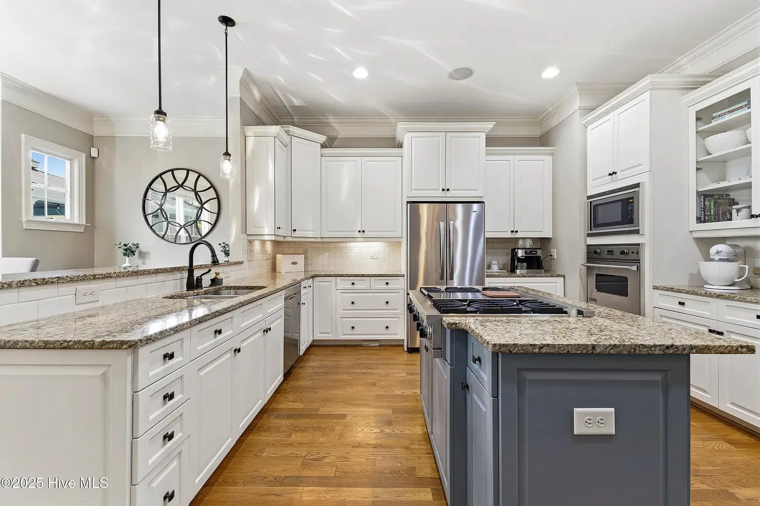 Modern kitchen with white cabinets, granite countertops, stainless steel appliances, and a large island.
