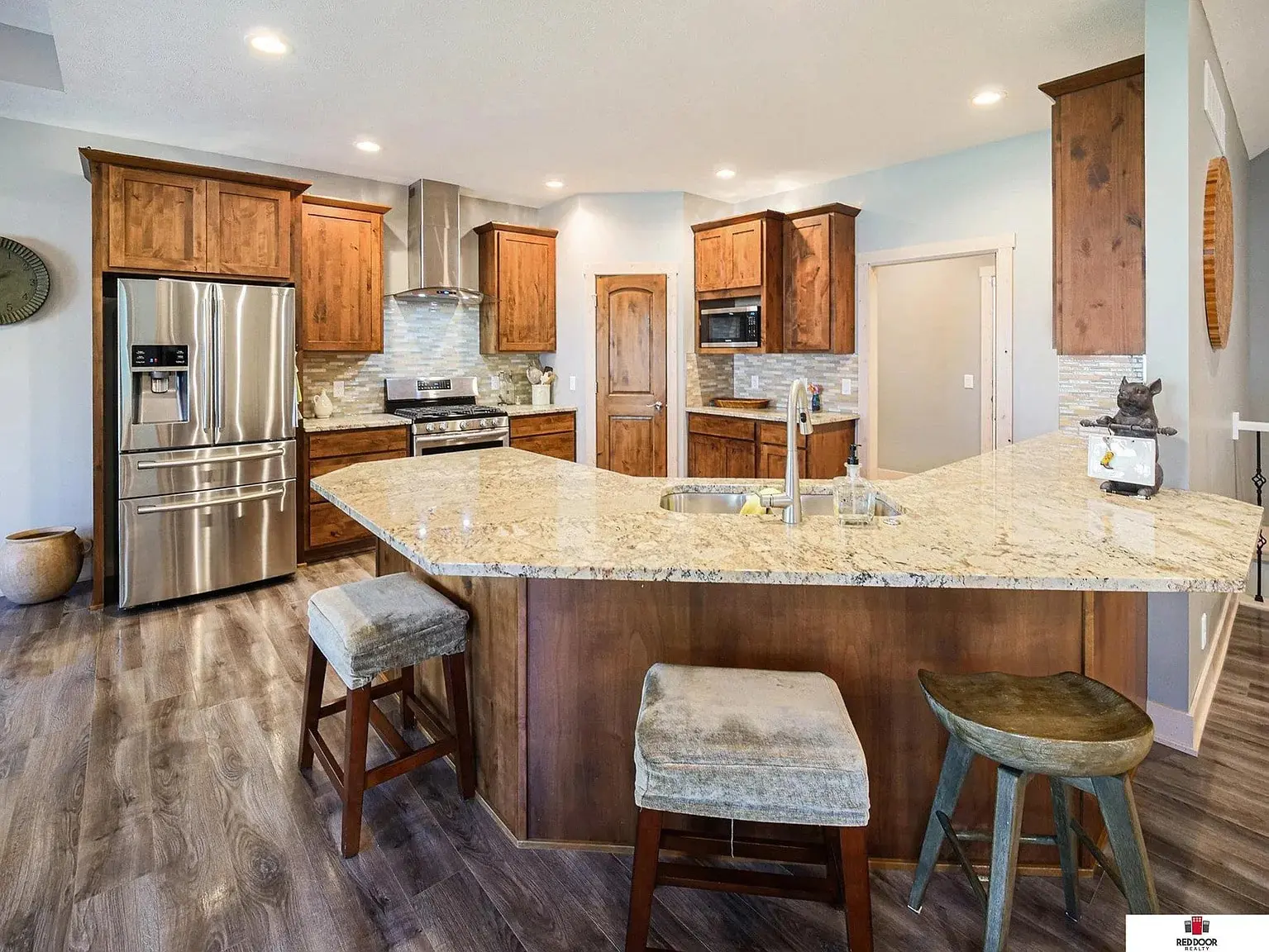 Modern kitchen with wooden cabinets, stainless steel appliances, and a large granite island with stools.