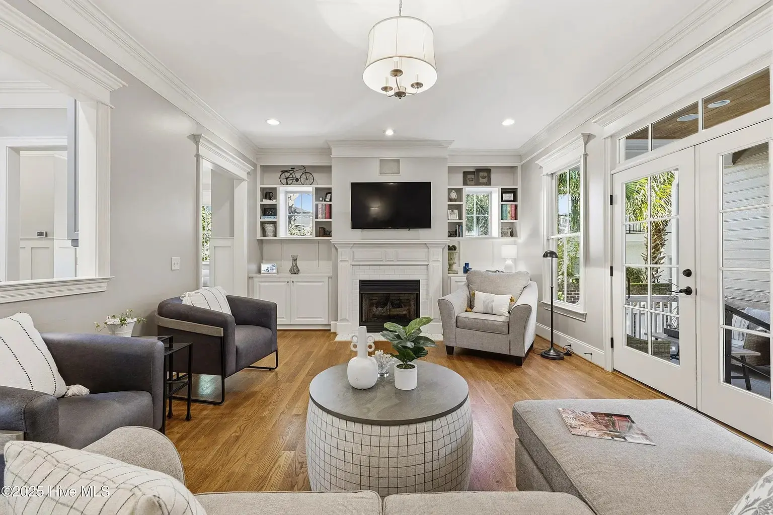 Modern living room with gray furniture, a round coffee table, fireplace, and wall-mounted TV.