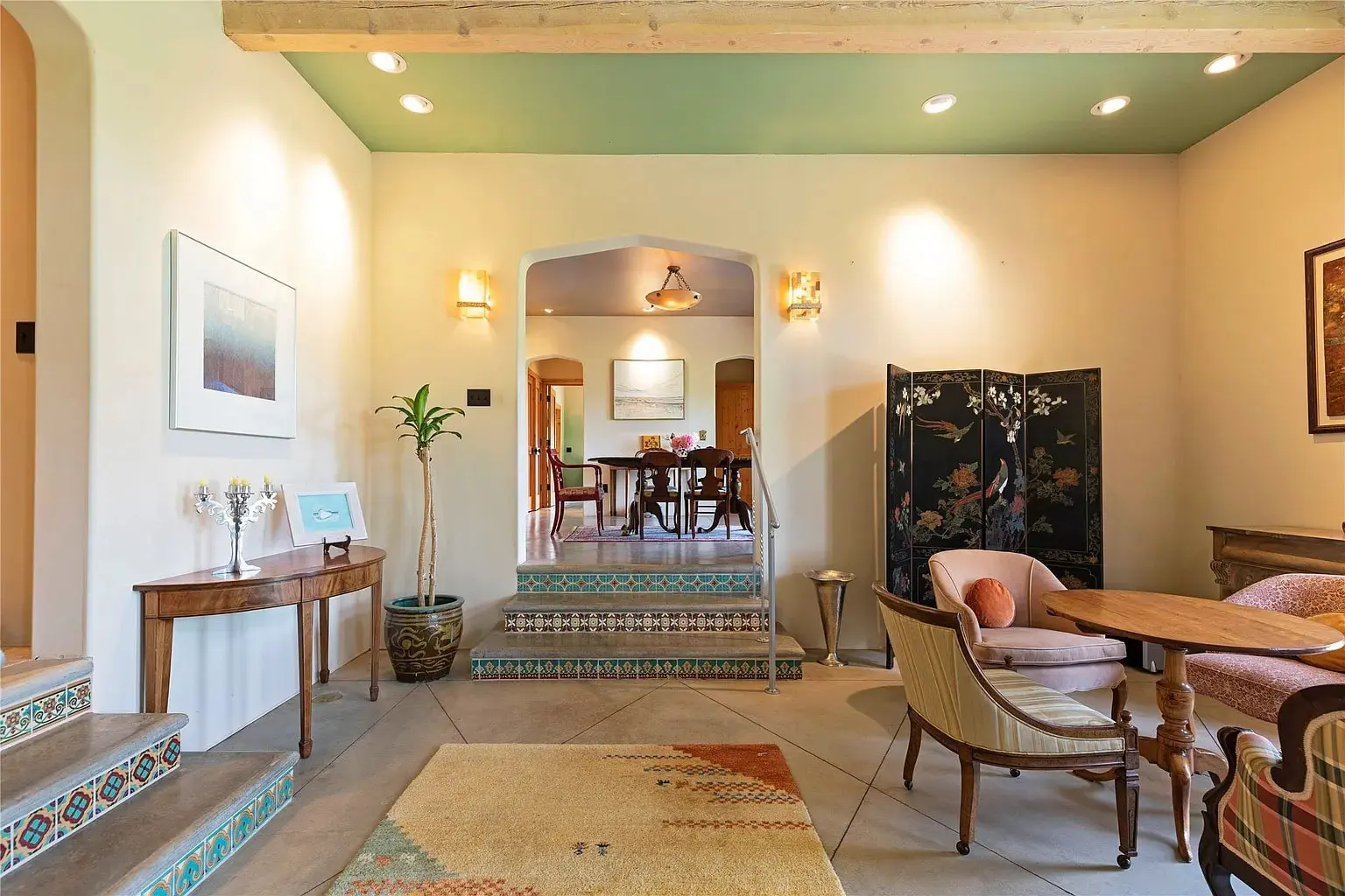 Cozy living room with vintage furniture, decorative screen, and view into a dining area.