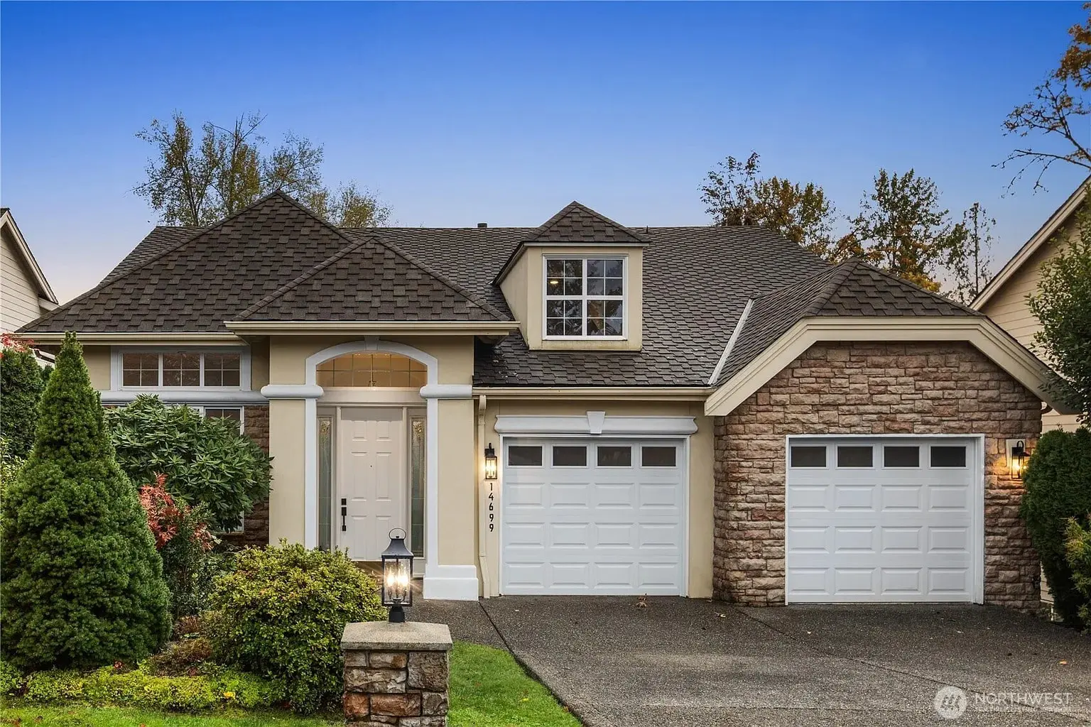 Single-story house with stone and siding exterior, two garages, and a well-maintained front yard.