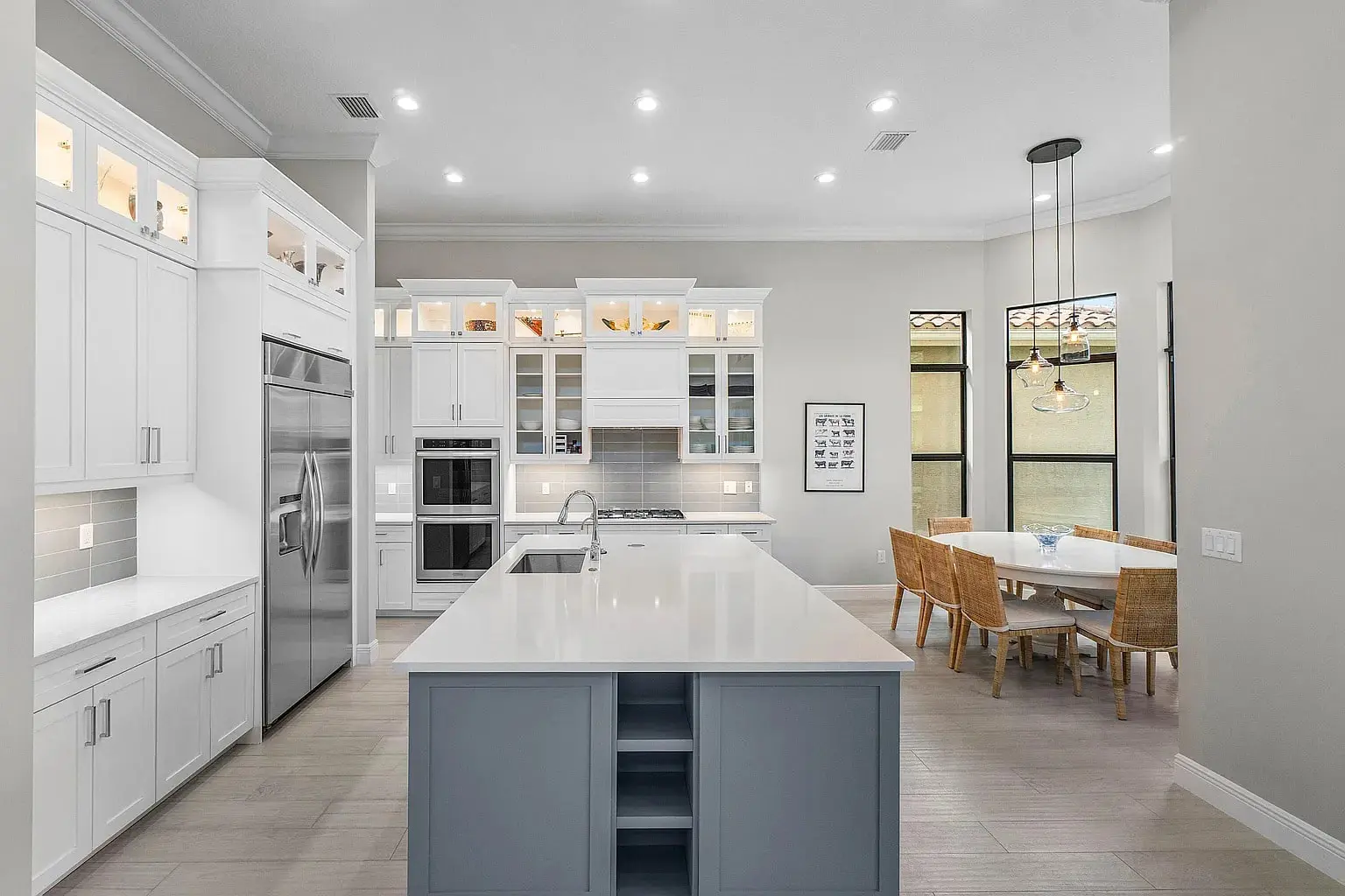 Modern kitchen with white cabinets, stainless steel appliances, large island, and adjacent dining area.