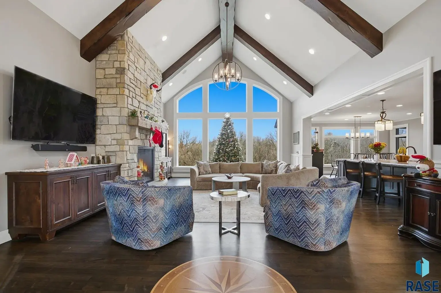 Spacious living room with vaulted ceiling, large windows, fireplace, and modern furnishings.