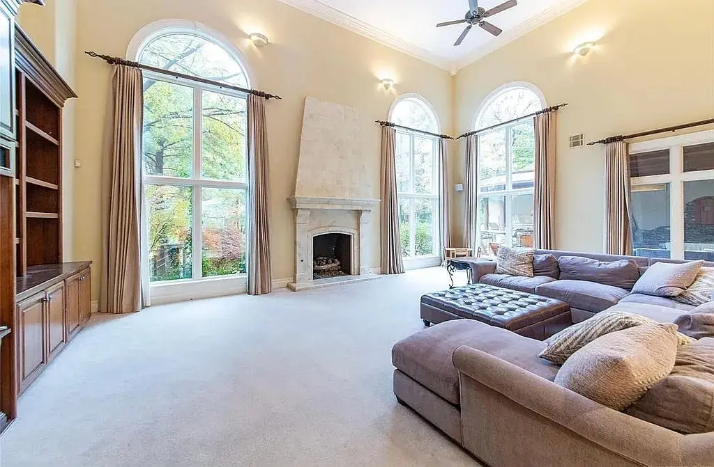 Spacious living room with large arched windows, a fireplace, and a sectional sofa.