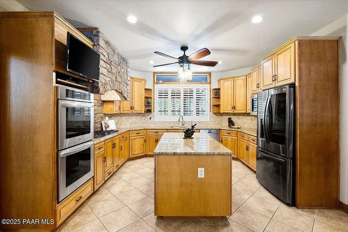 Spacious kitchen with wooden cabinets, stone accent wall, island, and stainless steel appliances.