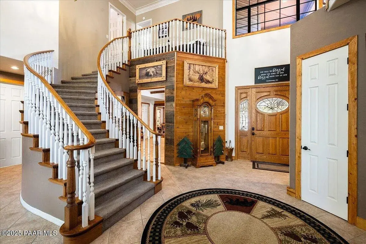 Spacious foyer with a curved staircase, wooden accents, and wildlife-themed decor.