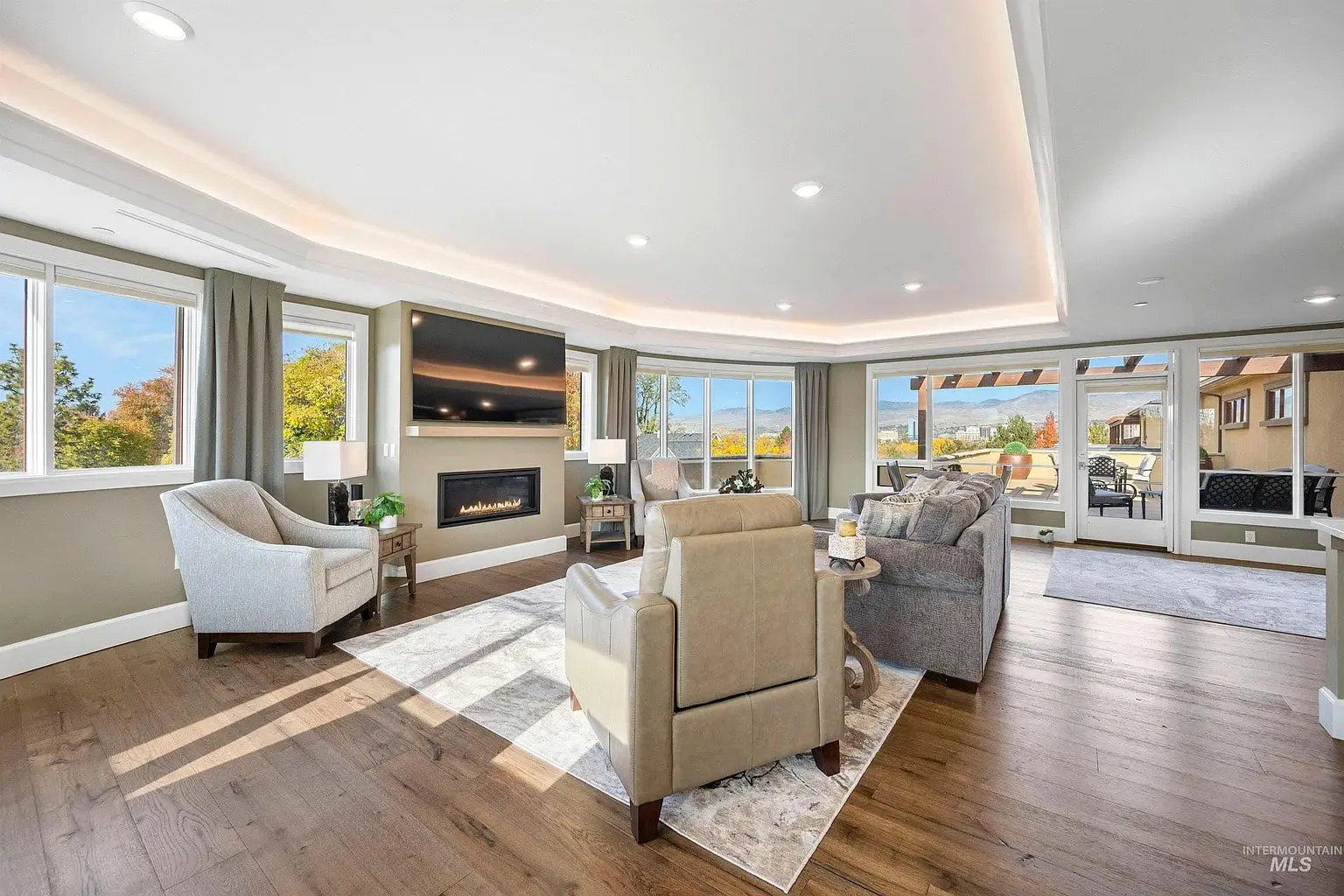 Spacious living room with large windows, modern furniture, fireplace, and outdoor patio access.