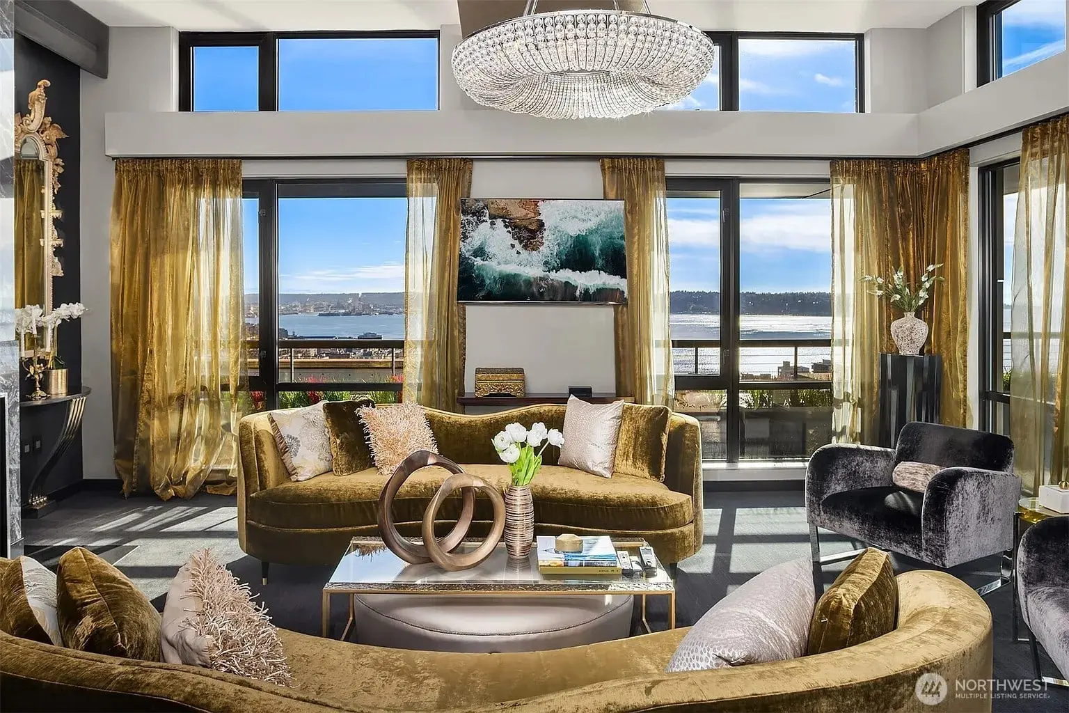 Luxurious living room with velvet furniture, large windows, ocean view, and a chandelier.
