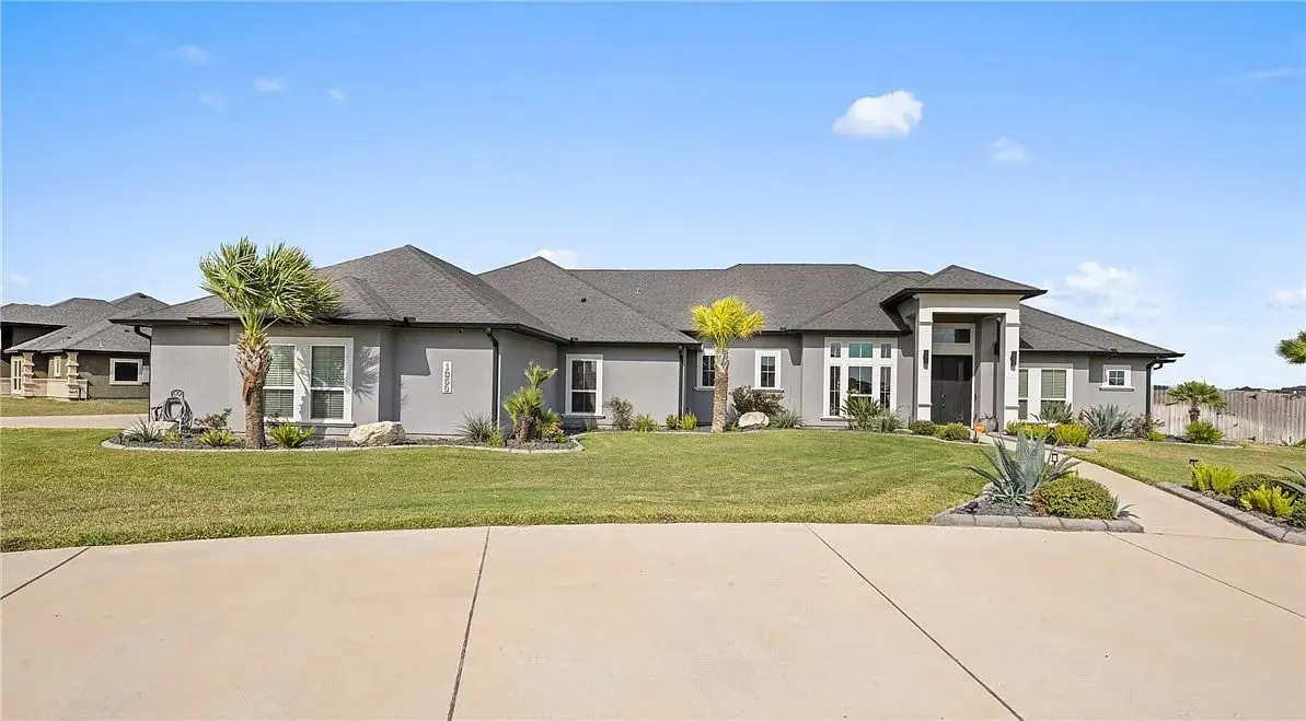 Single-story modern house with gray exterior, black roof, and landscaped front yard.