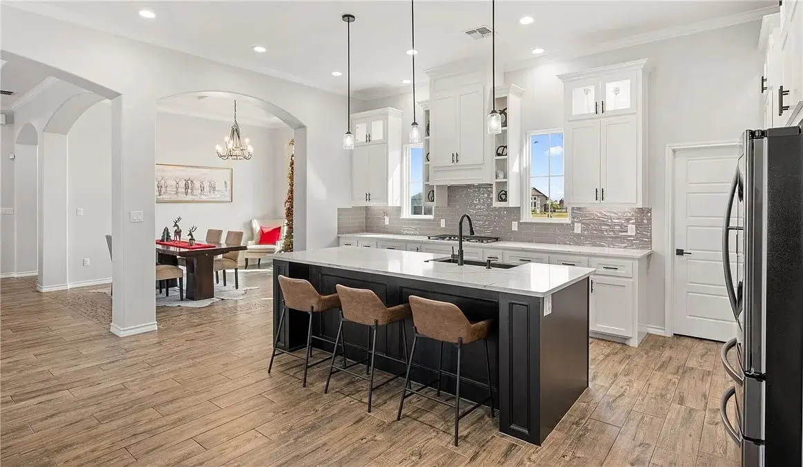Modern kitchen with large island, pendant lights, and adjacent dining area with a chandelier.