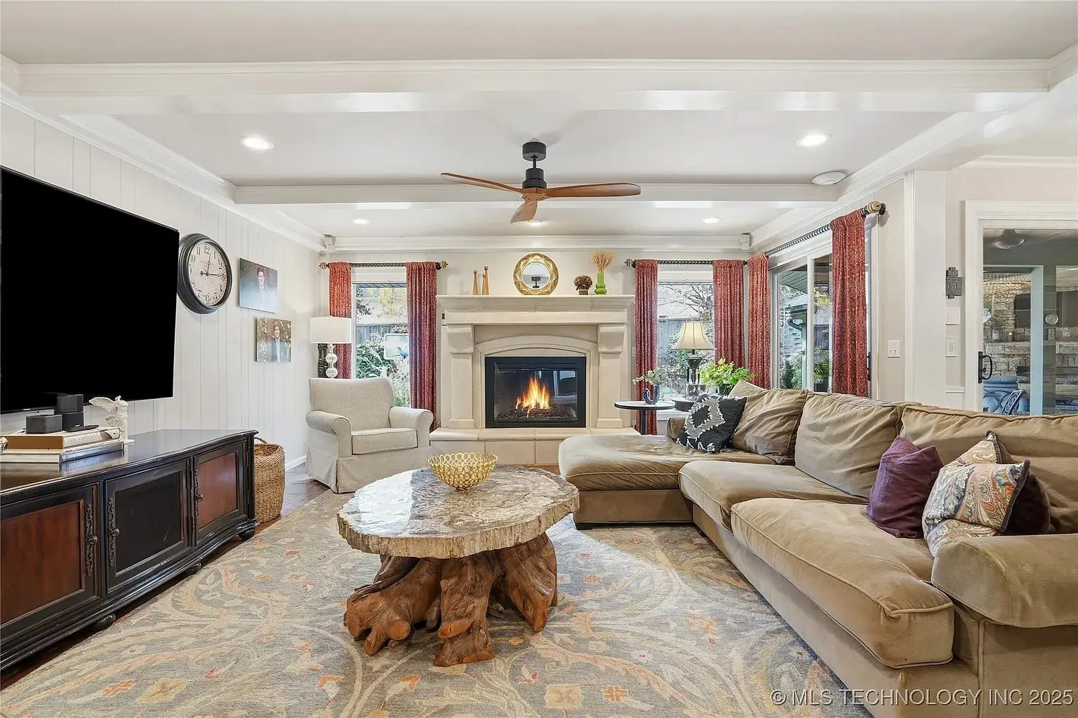 Living room with a large sectional sofa, stone fireplace, and tree trunk coffee table.