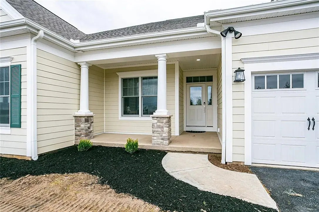 Front view of a modern house with a porch, columns, and attached garage.