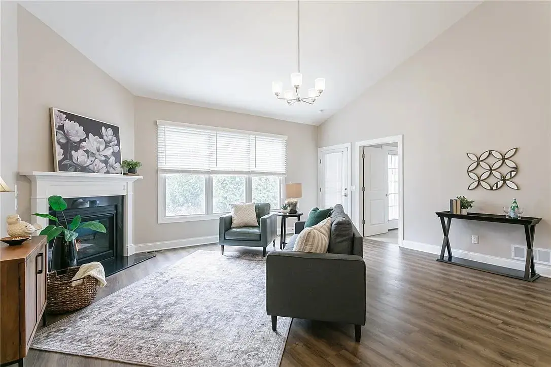 Spacious living room with a fireplace, large window, and modern furniture on wooden flooring.